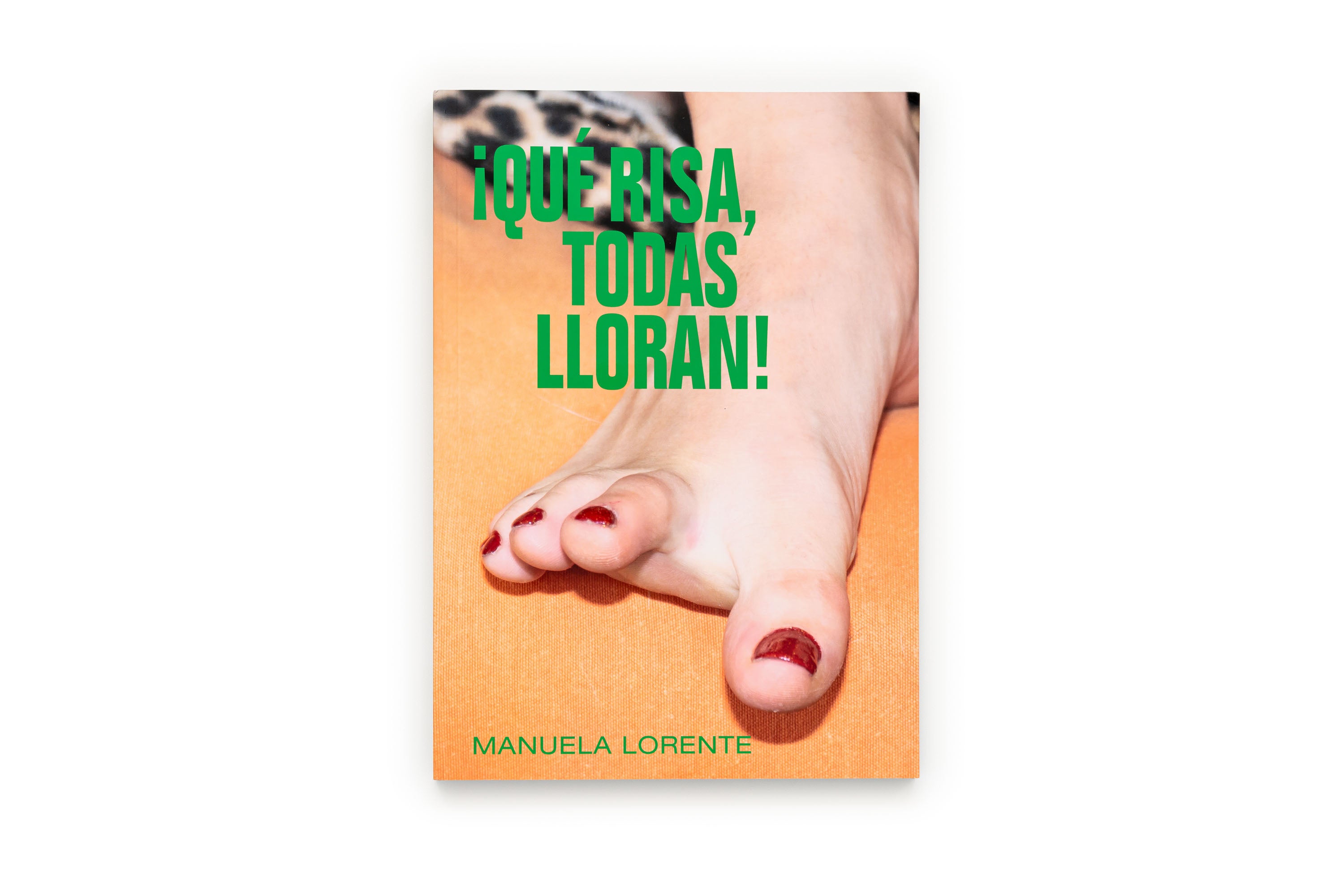 A book cover titled '¡QUE RISA, TODAS LLORAN!' by Manuela Lorente, featuring a close-up photo of a foot with red toenail polish on an orange background.